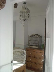 Pasillo con cómoda de madera, jaula decorativa y lámpara de cristal colgante