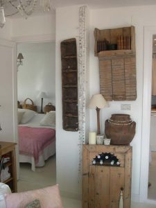 Pared con estantería de madera recuperada, tinaja y mueble bodeguero