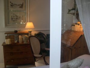 Rincón de lectura con cómoda de madera, silla clásica y escritorio antiguo
