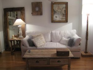 Salón con sofá blanco, mesa de centro de madera y espejo de marco grueso
